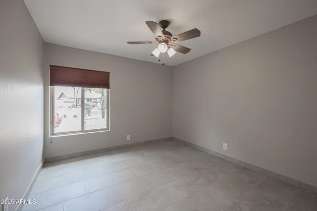 an empty room with a window and a fan