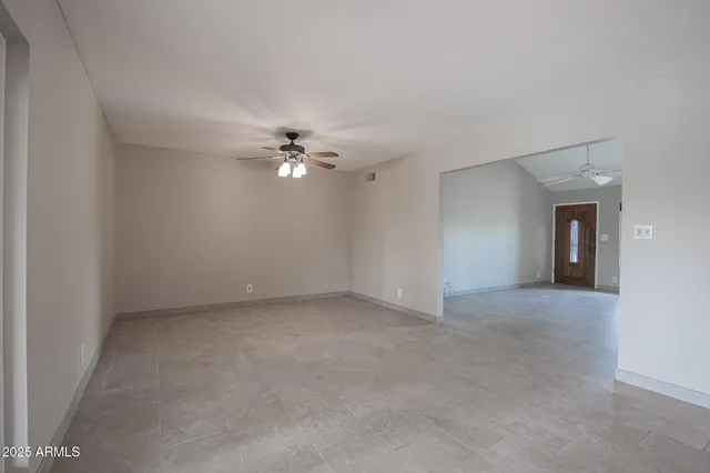 a view of an empty room with a chandelier fan