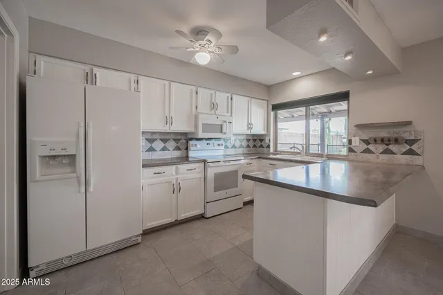 a kitchen with white cabinets and white appliances