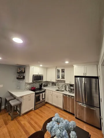 a kitchen with a refrigerator a microwave a stove and a sink with wooden floor