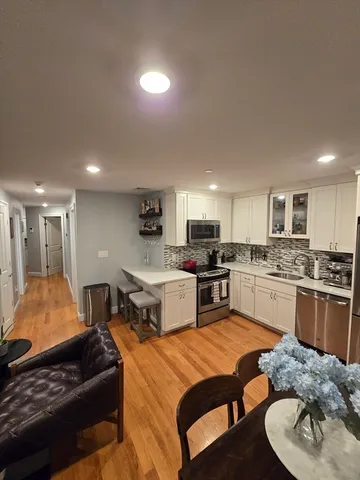 a large kitchen with a large counter top space a sink stainless steel appliances and cabinets