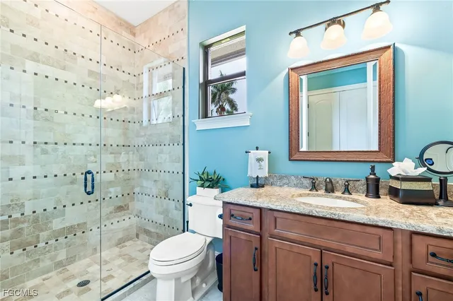 a bathroom with a granite countertop toilet a sink a mirror and a shower