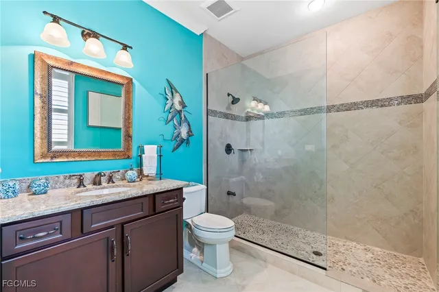 a bathroom with a shower sink vanity mirror and toilet