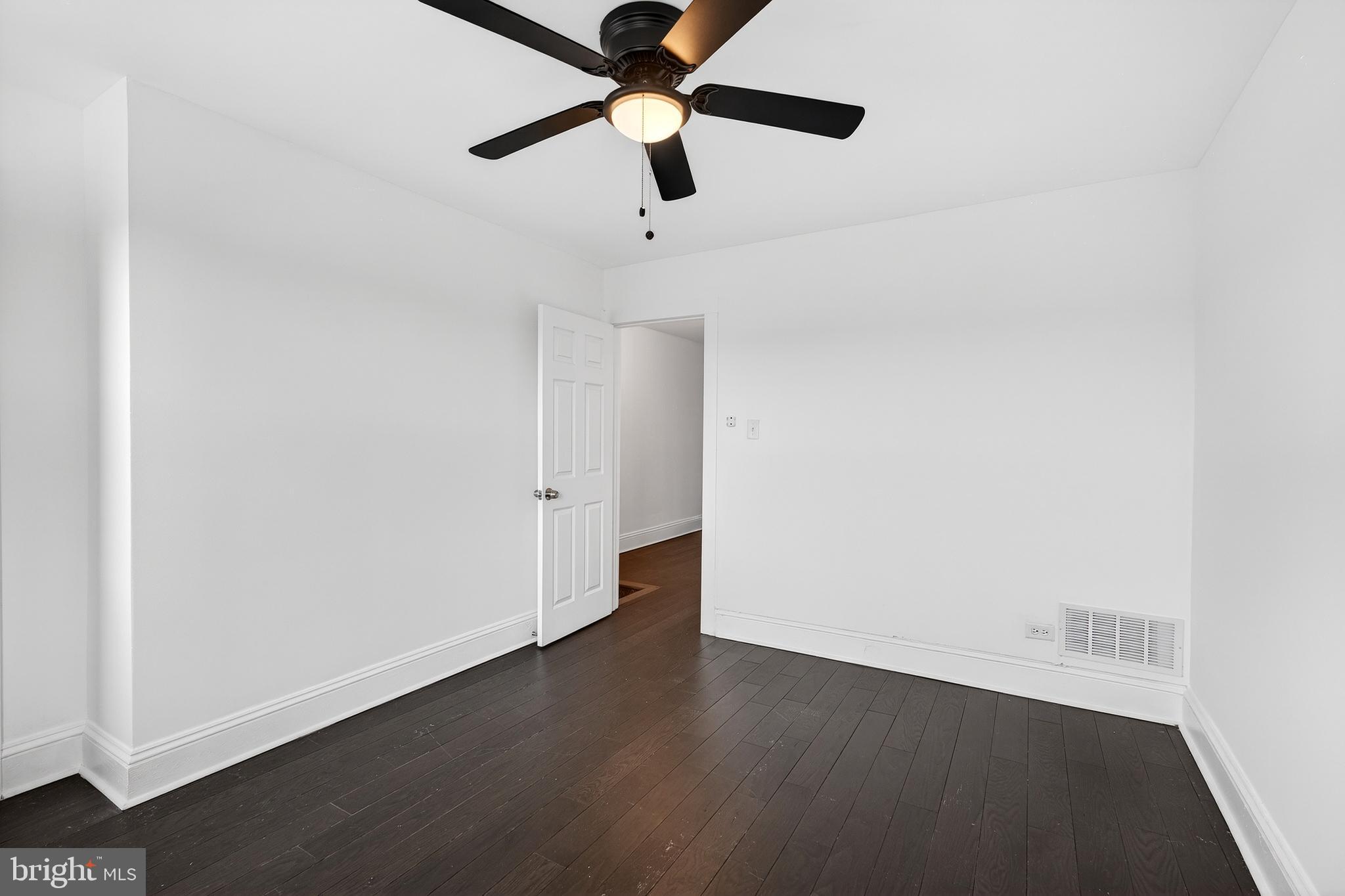 7014 Belclare Road Baltimore, MD 21222 - Photo 11 of 36 an empty room with wooden floor ceiling fan and windows
