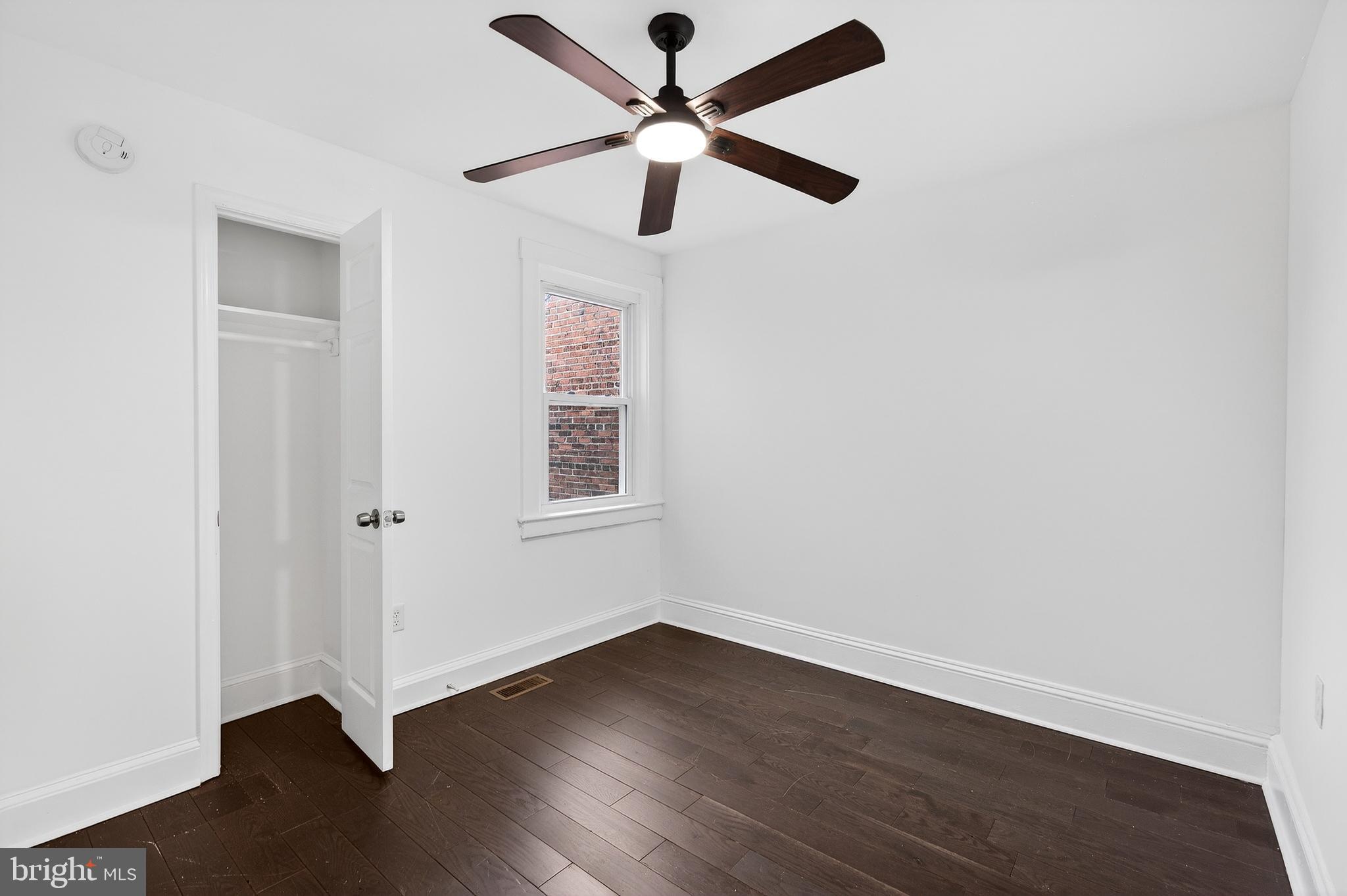 7014 Belclare Road Baltimore, MD 21222 - Photo 24 of 36 an empty room with wooden floor ceiling fan and windows