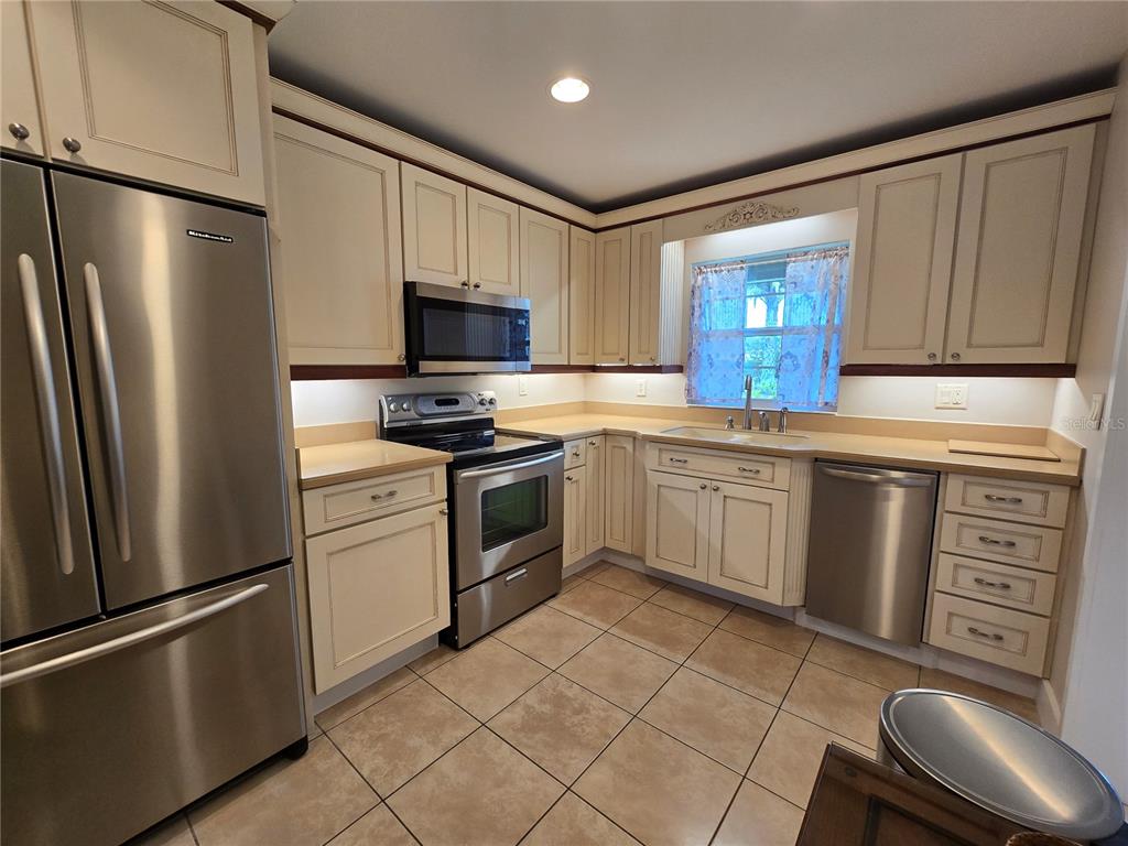 1640 Juno Trail, Unit 103C Astor, FL 32102 - Photo 8 of 20 a kitchen with white cabinets stainless steel appliances and a sink