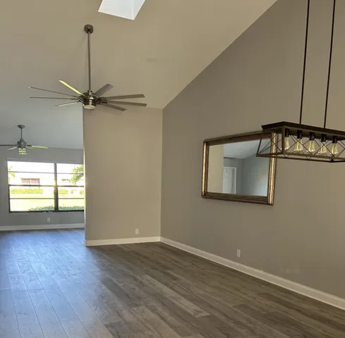 a kitchen with stainless steel appliances granite countertop a refrigerator a sink dishwasher a stove and white cabinets with wooden floor