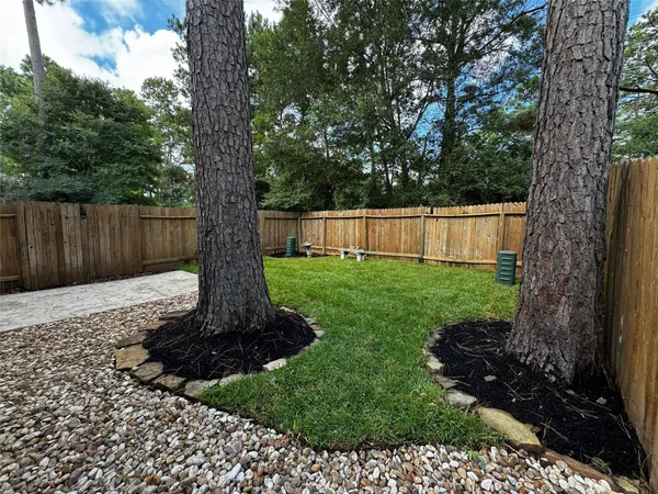 a view of a backyard with large trees and wooden fence