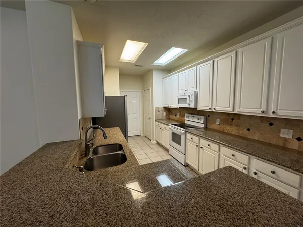 a kitchen with granite countertop a sink stove and cabinets