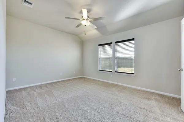 an empty room with chandelier fan and windows