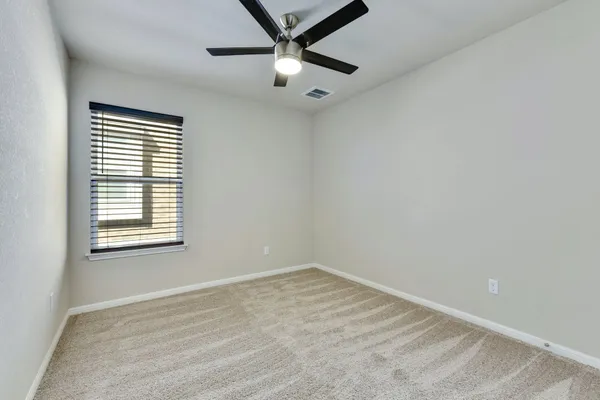 an empty room with a window and a ceiling fan