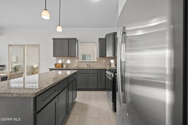 a kitchen with granite countertop a refrigerator and a sink