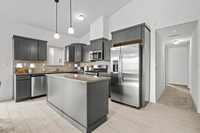 a kitchen with stainless steel appliances granite countertop a refrigerator a sink a stove a microwave and wooden floor