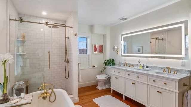 a bathroom with a double vanity sink toilet mirror and shower