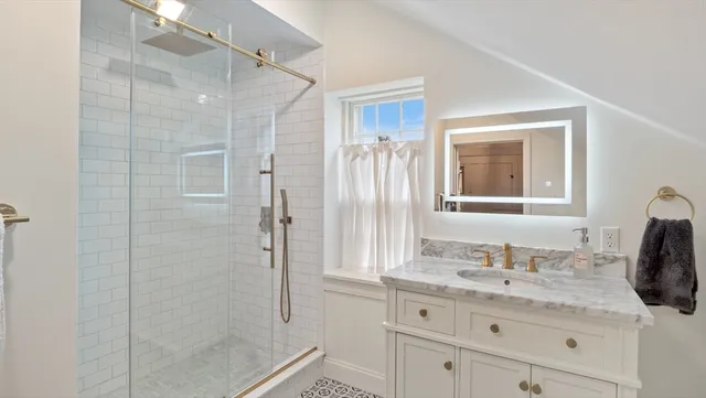 a bathroom with a granite countertop sink a mirror and shower