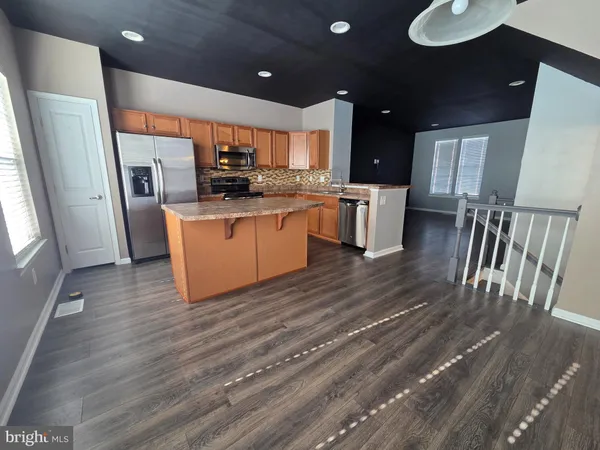 a kitchen with refrigerator and wooden floor