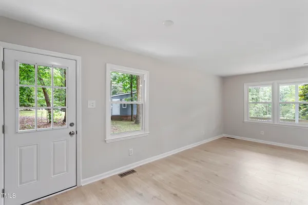 a view of an empty room with wooden floor and a window