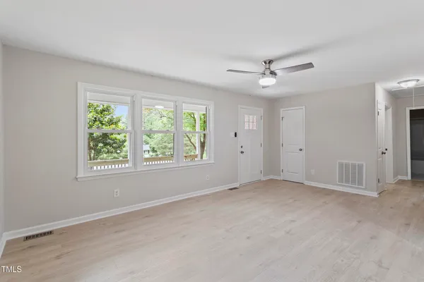an empty room with windows and fan