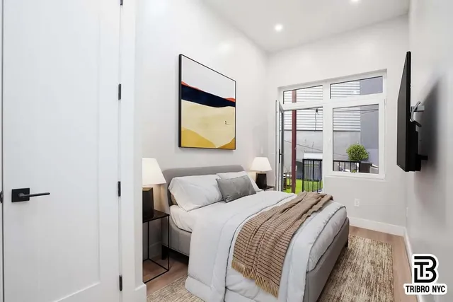 a bedroom with a bed a flat screen tv and painting on the wall