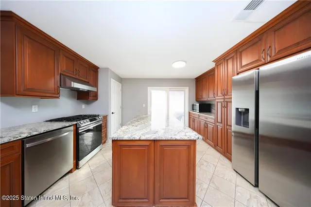 a kitchen with stainless steel appliances granite countertop a stove a sink and a refrigerator