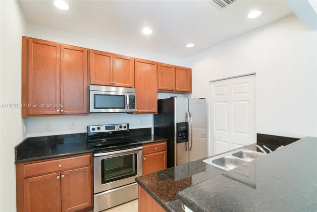 a kitchen with stainless steel appliances granite countertop a refrigerator stove and sink