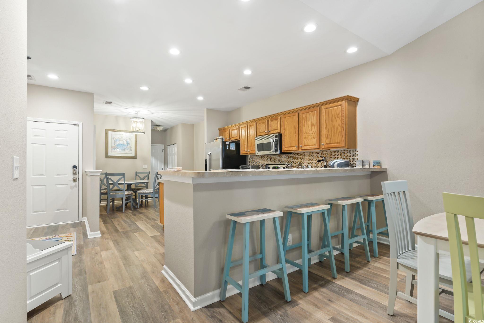 430 Woodpecker Lane, Unit D Murrells Inlet, SC 29576 - Photo 10 of 36 Kitchen featuring a kitchen bar, backsplash, a peninsula, light wood-type flooring, and recessed lighting