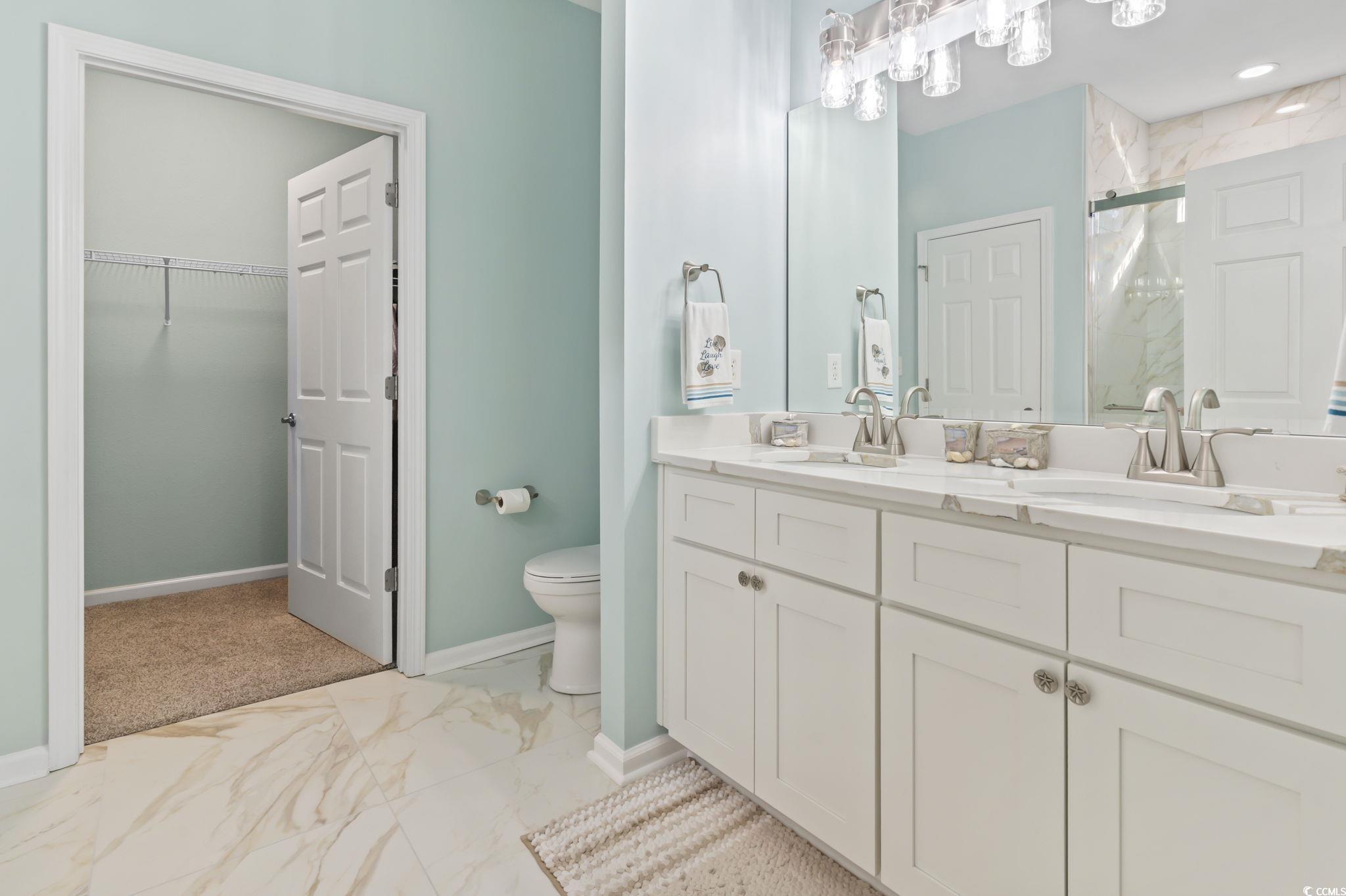 430 Woodpecker Lane, Unit D Murrells Inlet, SC 29576 - Photo 20 of 36 Bathroom featuring light marble finish floors, double vanity, a marble finish shower, and a spacious closet