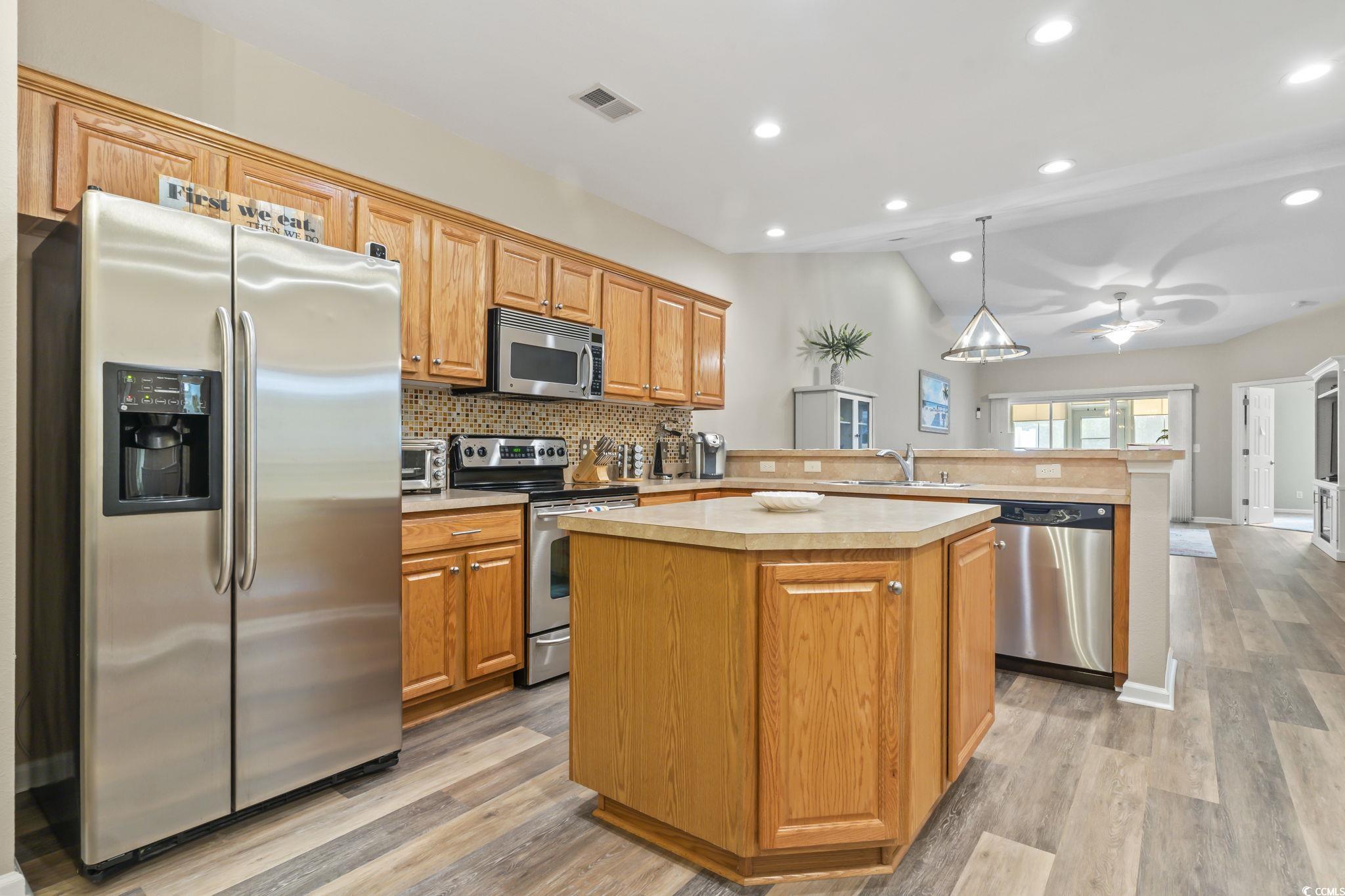 430 Woodpecker Lane, Unit D Murrells Inlet, SC 29576 - Photo 6 of 36 Kitchen featuring appliances with stainless steel finishes, light countertops, a peninsula, lofted ceiling, and hanging light fixtures