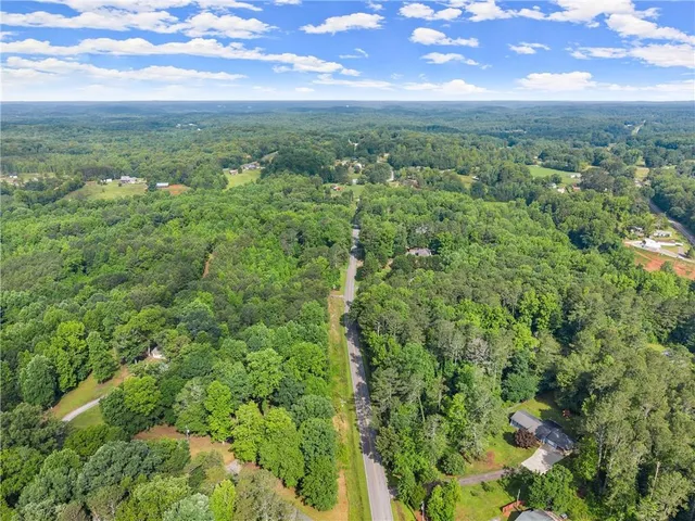 an aerial view of residential houses with outdoor space and trees