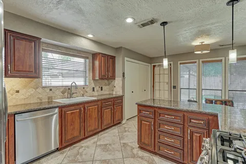 a kitchen with stainless steel appliances granite countertop a sink refrigerator and cabinets
