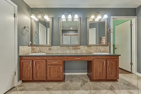 a bathroom with a granite countertop shower a mirror and a sink