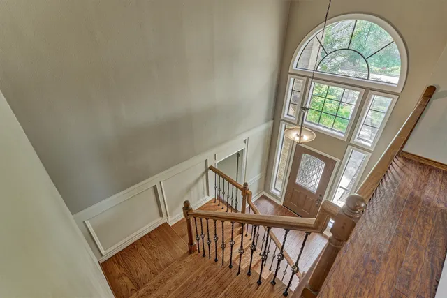 a view of staircase with large window wooden floor and a rug