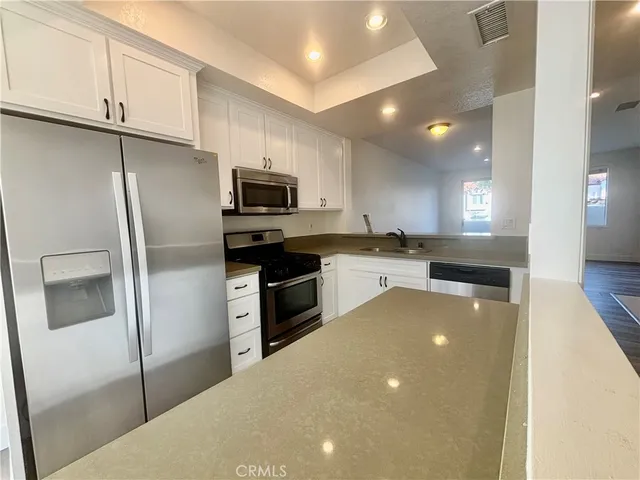 a kitchen with kitchen island a counter top space cabinets stainless steel appliances and a refrigerator