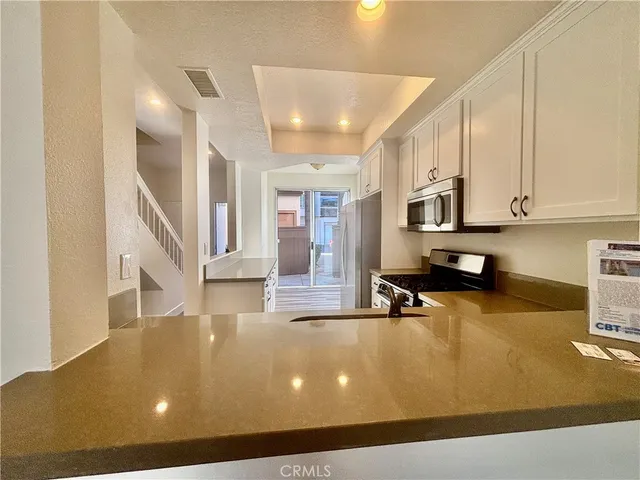 a view of a living room with kitchen appliances