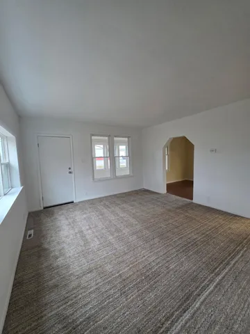 a view of empty room with window and wooden floor