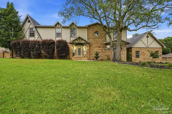 a view of a house with a big yard and large tree