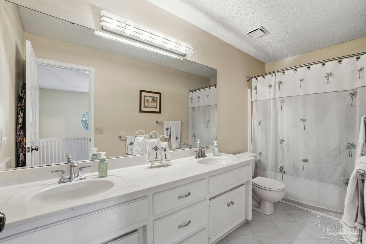 1437 Kings Road Cantonment, FL 32533 - Photo 48 of 67 a bathroom with double vanity sinks a toilet a shower a vanity and a mirror