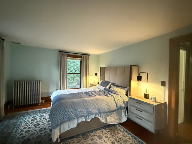 a spacious bedroom with a bed and wooden floor