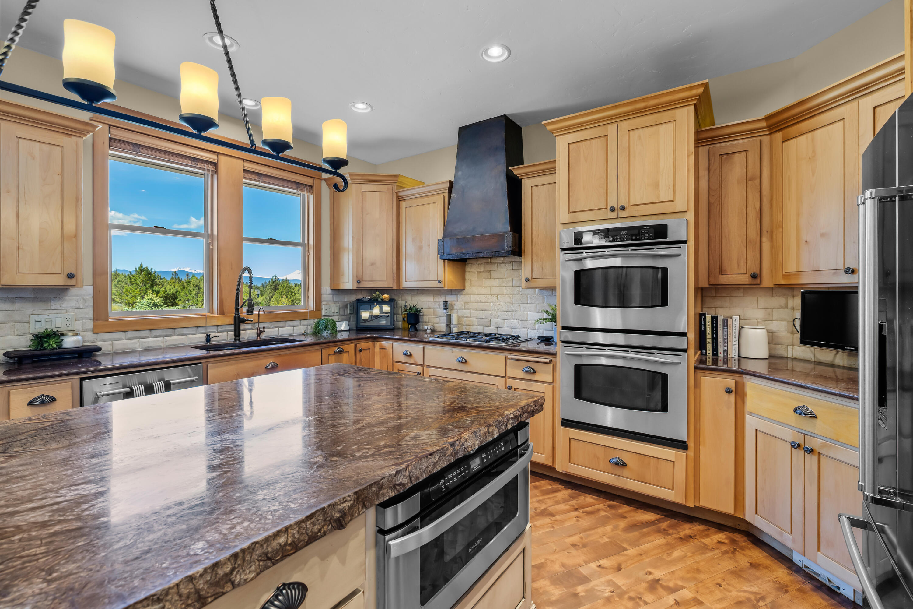 64145 Hunnell Road Bend, OR 97703 - Photo 14 of 65 The kitchen is positioned to capture Cascade Mountain views, with warm cabinetry, a generous island, double ovens and an easy connection to the dining area for everyday living and entertaining.