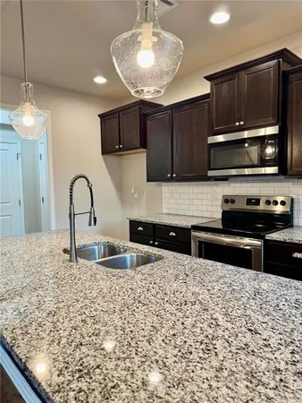 a kitchen with stainless steel appliances granite countertop a stove a sink and a microwave