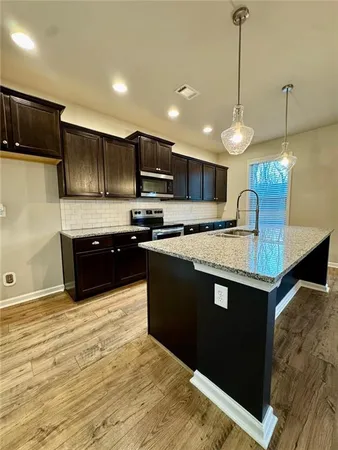 a kitchen with stainless steel appliances granite countertop a sink a stove and a refrigerator