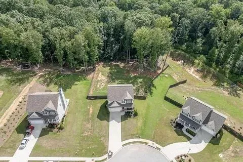 aerial view of a house with garden space and a lake view