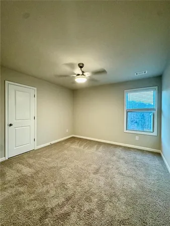 an empty room with a ceiling fan and window