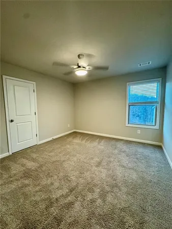 an empty room with a ceiling fan and window