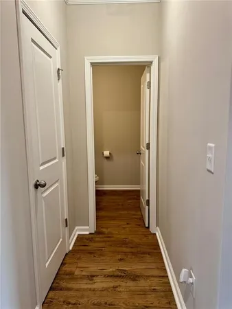 a view of a hallway with wooden floor and a bathroom