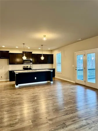a view of kitchen with stainless steel appliances kitchen island large window and wooden floor