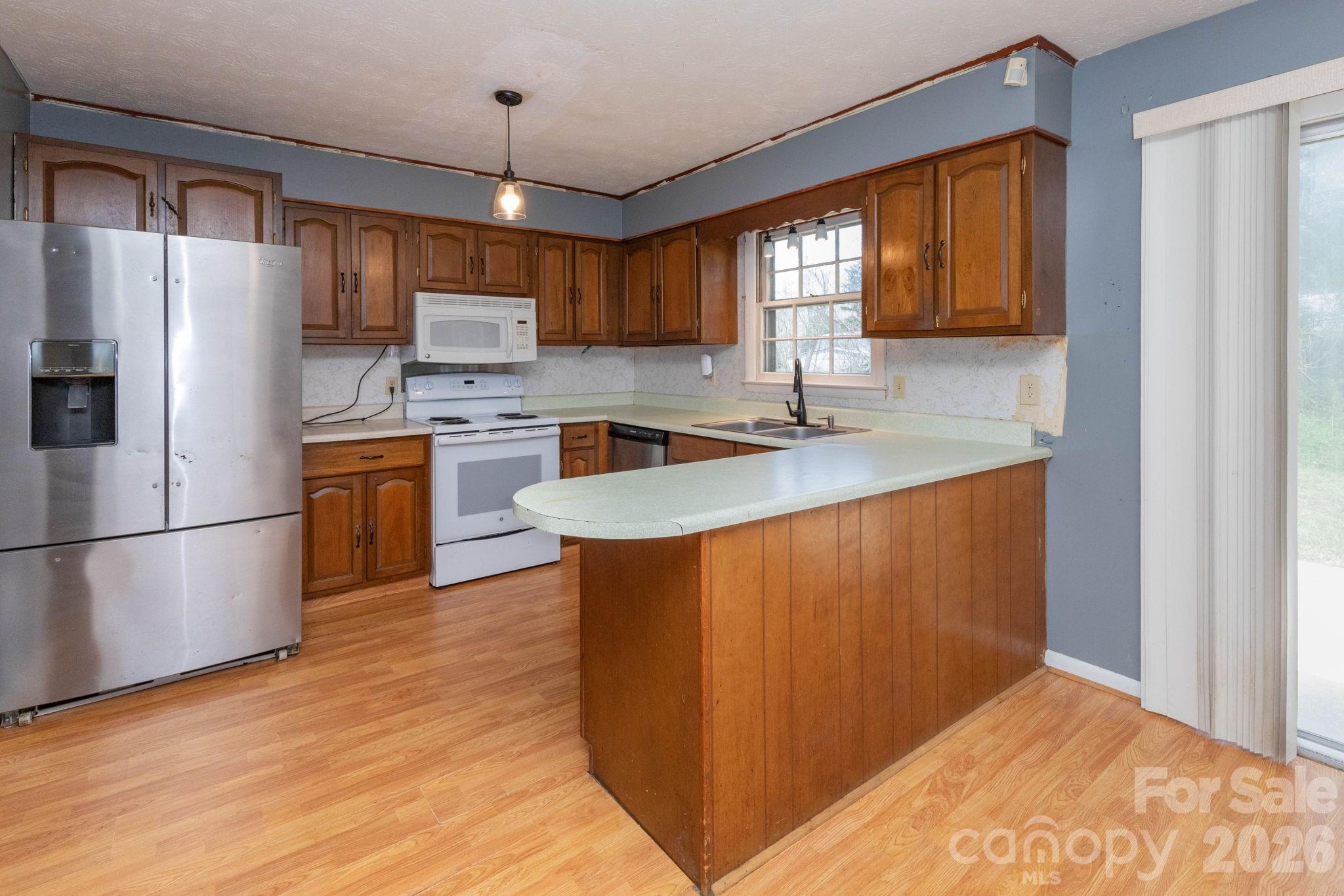 380 Woodland Church Road Clyde, NC 28721 - Photo 5 of 23 a kitchen with stainless steel appliances granite countertop a refrigerator a sink dishwasher a stove with wooden cabinets and floor
