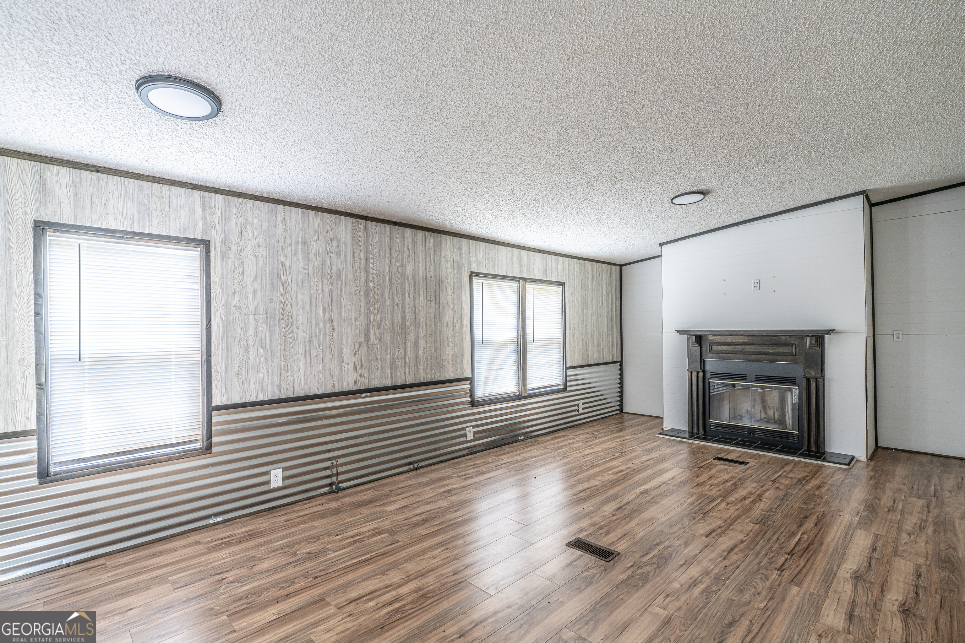 71 Kirk Road Northwest White, GA 30184 - Photo 6 of 43 an empty room with wooden floor fireplace and windows
