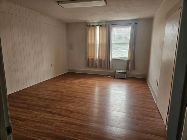 a view of an empty room with wooden floor and a window