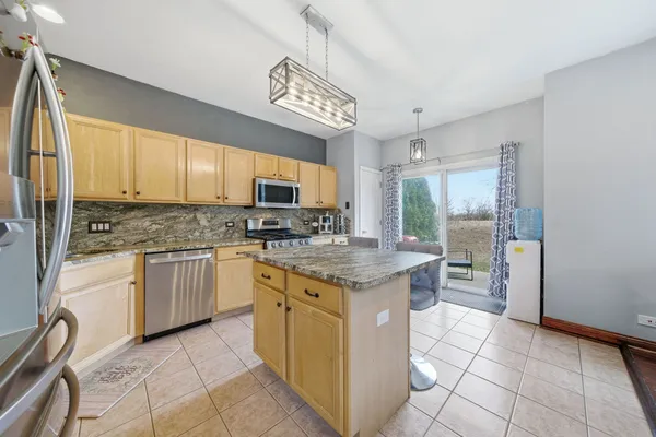 a kitchen with stainless steel appliances granite countertop a stove top oven a refrigerator a sink and dishwasher with white cabinets